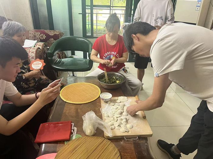 圖為實踐團成員在認真幫助老人做飯包餃子的日常團隊成員攝